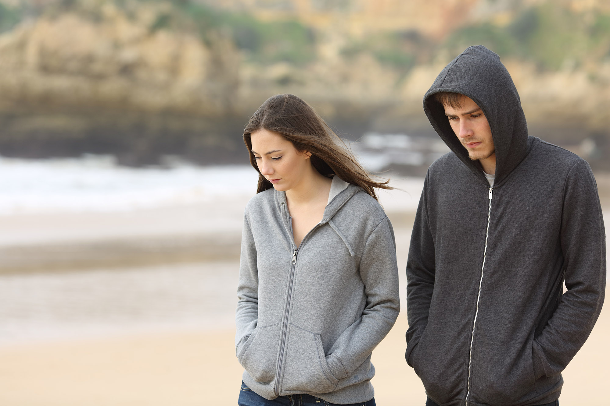 Couple of angry and sad teenagers together walking on the beach