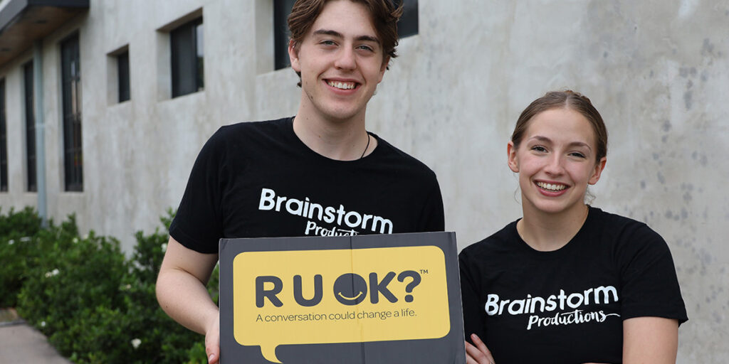 Two actors wearing Brainstorm Productions holding an R U OK? sign