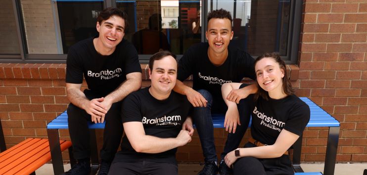 Four Brainstorm actors sitting on a school bench and smiling for the camera