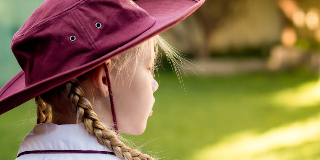 A primary school student wearing a school uniform is looking into the distance.