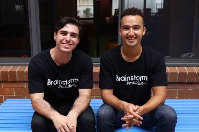 Two actors sitting on a school table