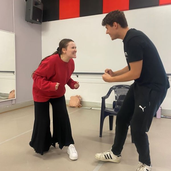 Two actors in rehearsal looking at each other in celebration