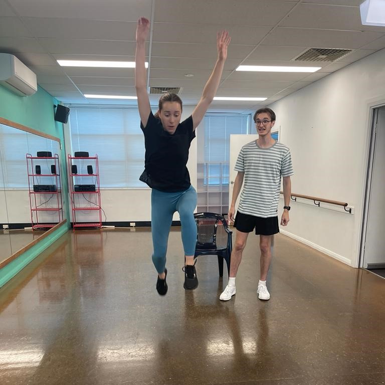 Two actors in rehearsal - one is jumping in the air