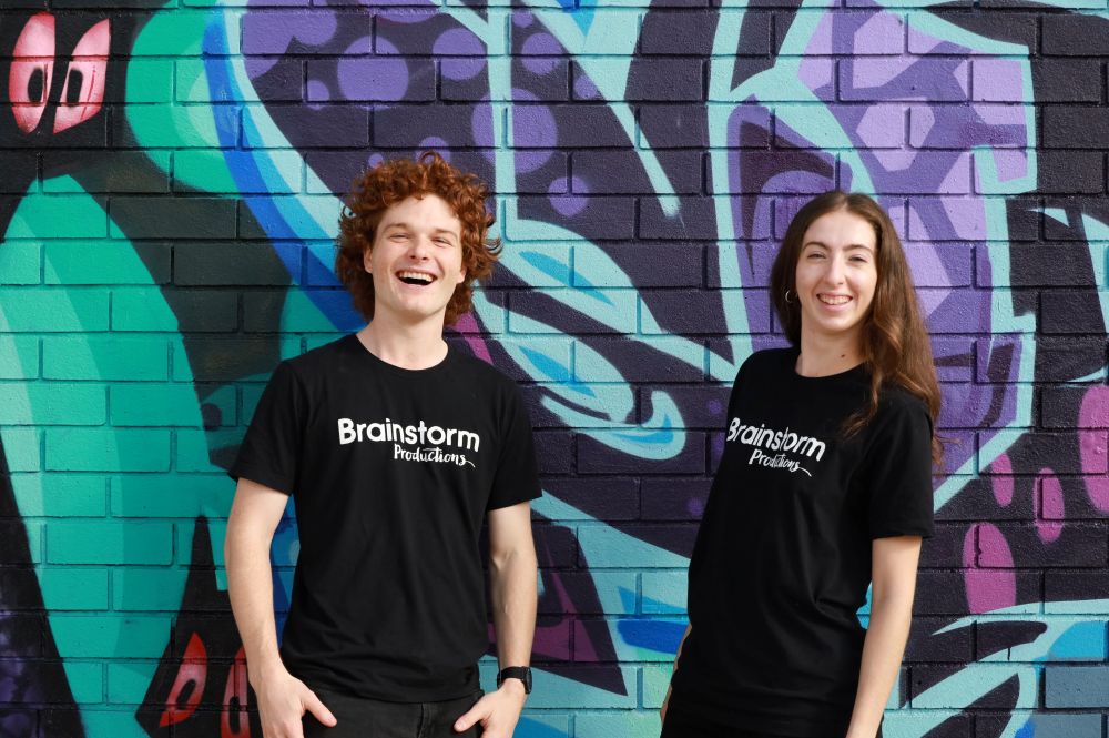 Two happy young actors are laughing and smiling for the camera wearing Brainstorm Productions t-shirts