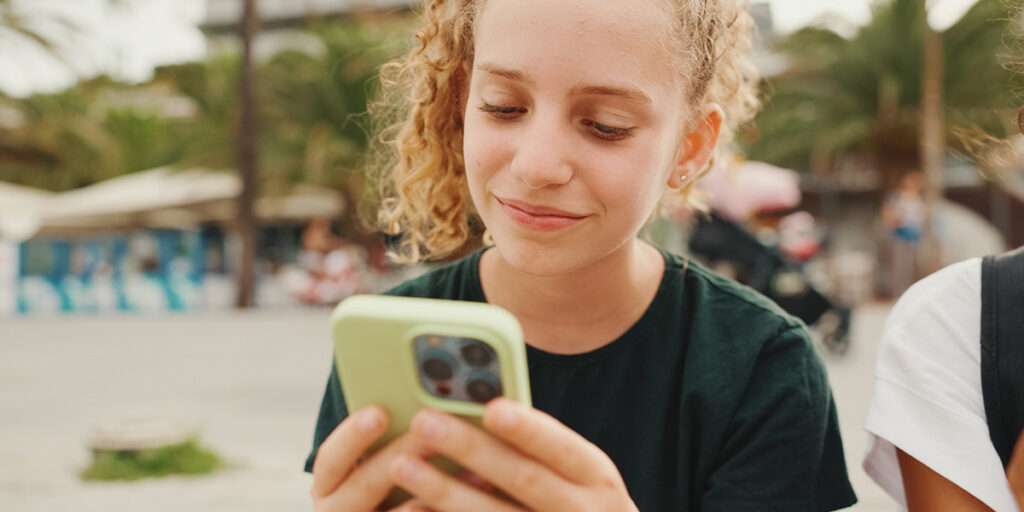 A young person smiling and looking at a phone - the hero image for a blog about Privacy Awareness Week