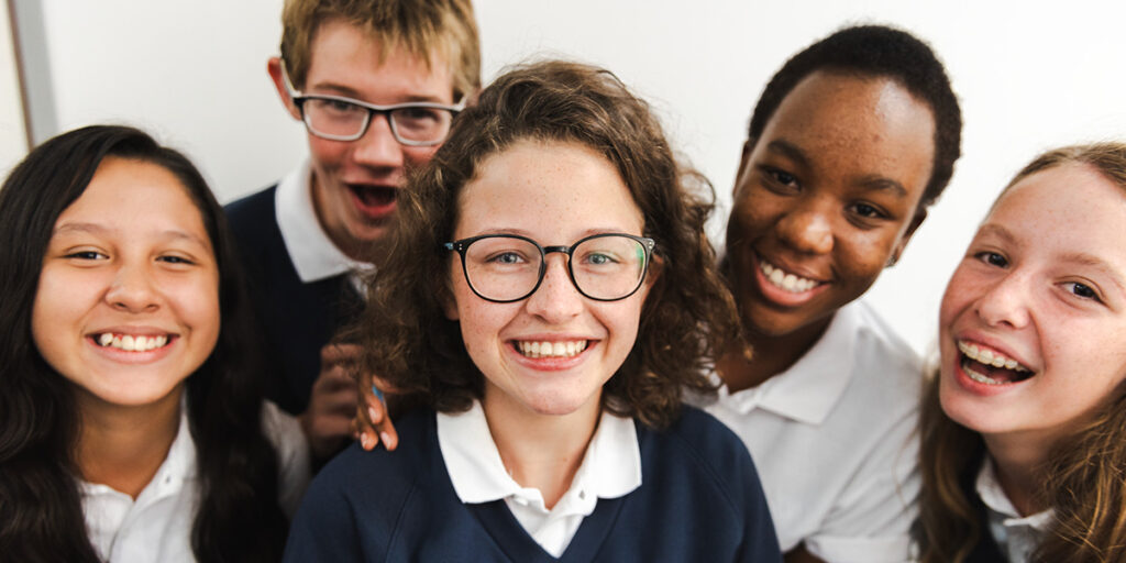 A group of high school students in uniforms are smiling for the camera