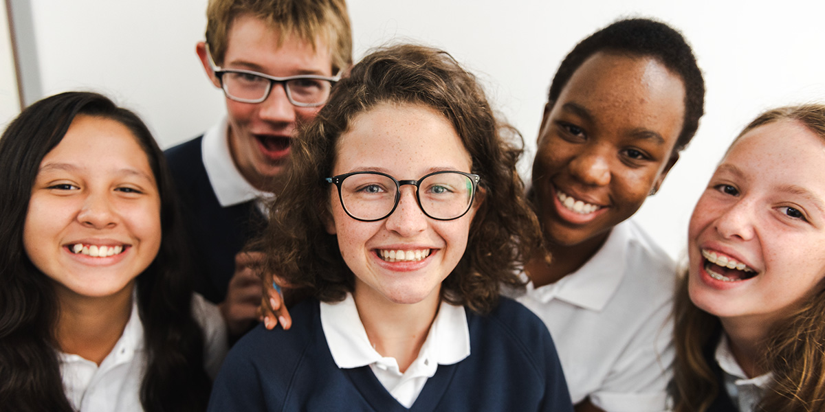 A group of high school students in uniforms are smiling for the camera