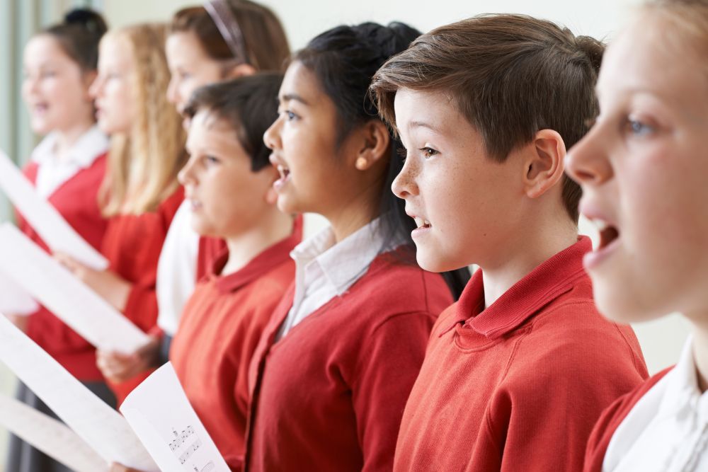 A group of middle school students singing in a classroom